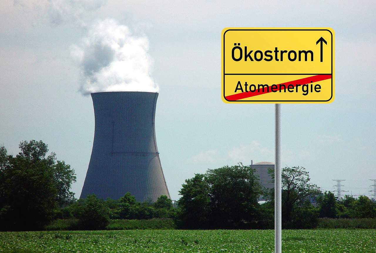 Ökostrom statt Atomenergie Schild mit Atomkraftwerk im Hintergrund